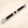 Barre de traction porte ajustable 60-100 cm seule, tube chromé, deux longues mousses noires et une mousse centrale à bagues rouges, patins transparents dans leurs coupelles chromées, vue de trois quarts sur fond crème
