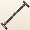 Barre de traction de porte sans perçage Lock Grip seule, en diagonale sur fond crème : patins octogonaux à bord rouge, molettes de verrouillage moletées et bagues rouges à chaque bout, deux mousses noires à bagues rouges, niveau à bulle vert au centre